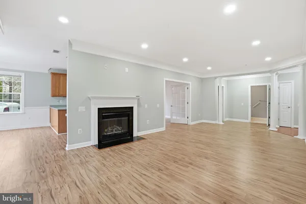 a view of an empty room with wooden floor fireplace and a window