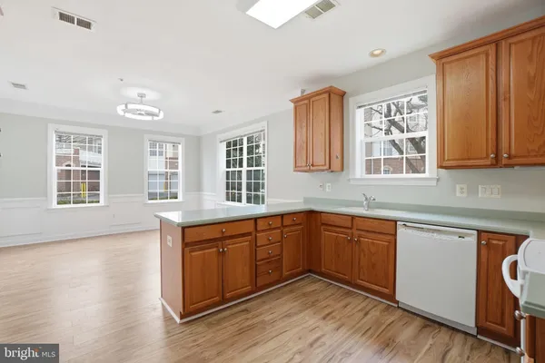 a kitchen with stainless steel appliances granite countertop wooden cabinets a sink and dishwasher with wooden floor