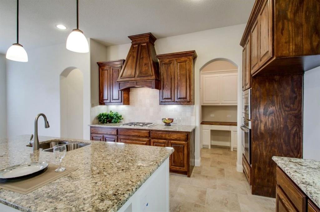 421 Prairie Run Aledo, TX 76008 - Photo 12 of 19 Kitchen featuring arched walkways, light stone countertops, hanging light fixtures, custom range hood, and stainless steel oven