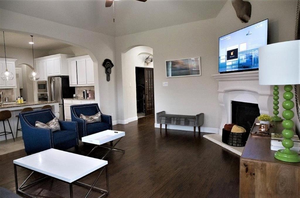421 Prairie Run Aledo, TX 76008 - Photo 3 of 19 Living room featuring ceiling fan, dark wood-style floors, a fireplace with raised hearth, and arched walkways
