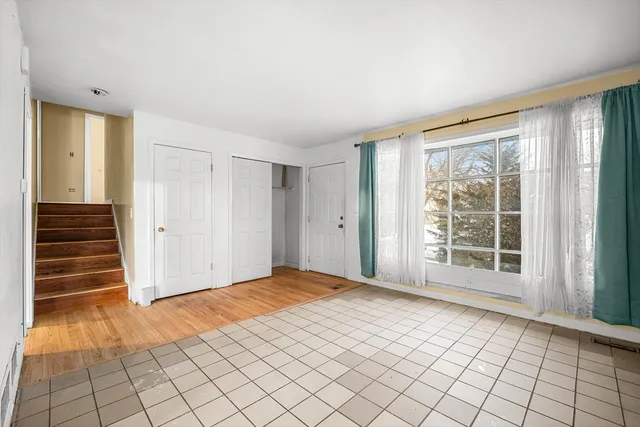 a view of an empty room with wooden floor and window
