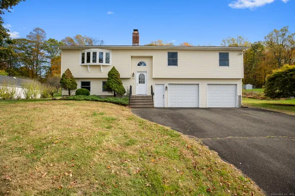 a view of a white house with a yard and a large tree