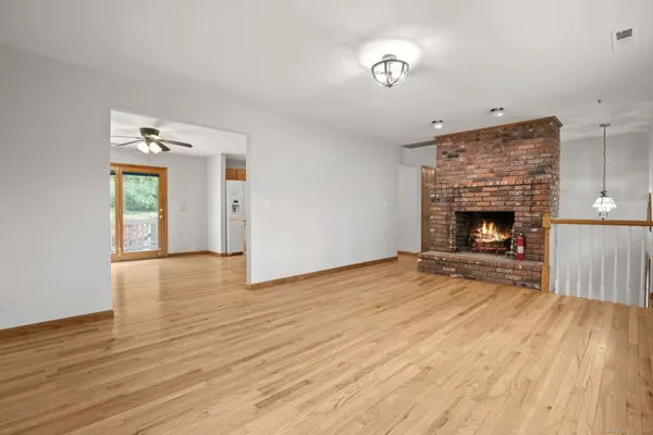 a view of an empty room with wooden floor fireplace and a window