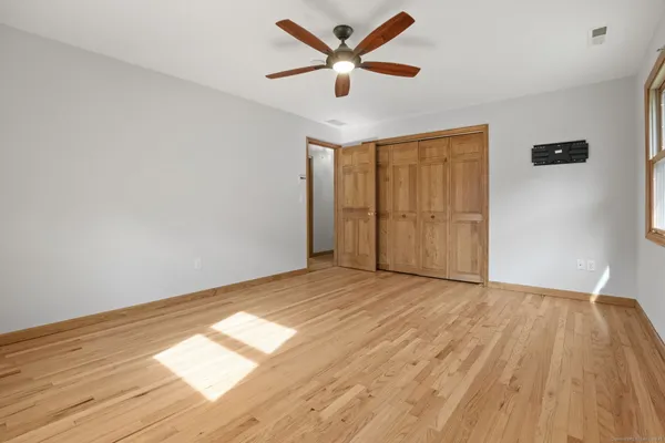 a view of empty room with wooden floor and fan