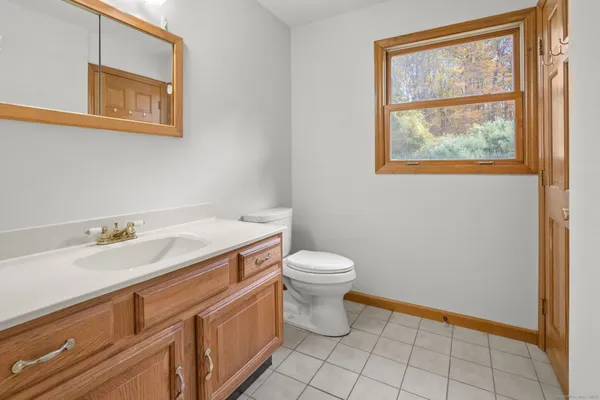 a bathroom with a granite countertop toilet a sink and a window