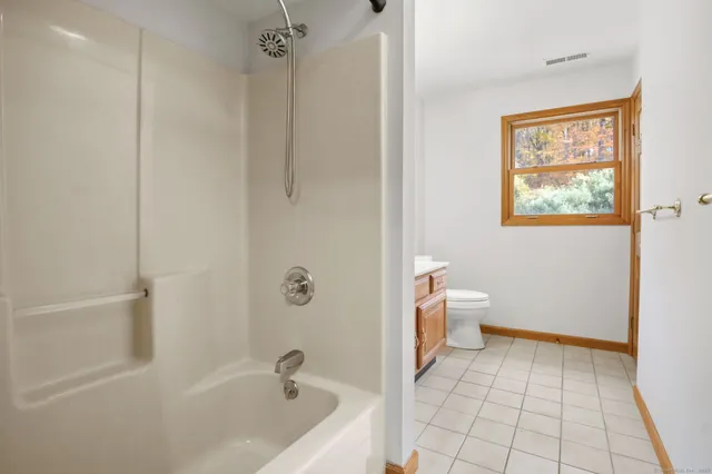 a bathroom with a granite countertop toilet a sink and a window