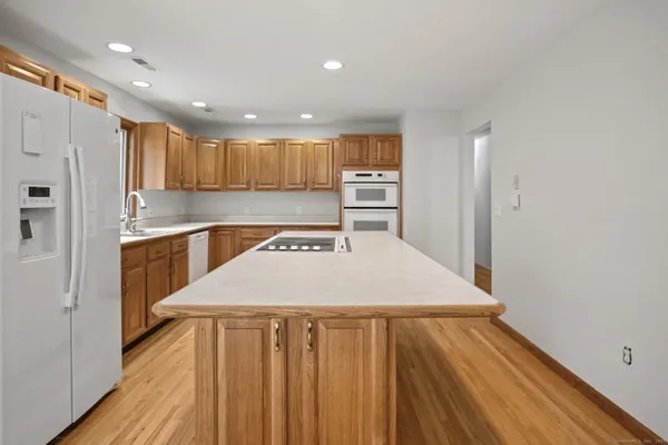 a kitchen with kitchen island a sink dishwasher a stove and white cabinets with wooden floor