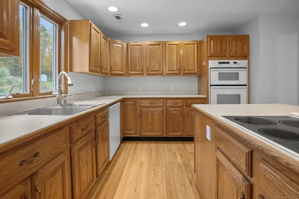 a kitchen with stainless steel appliances kitchen island granite countertop a sink counter space cabinets and a large window