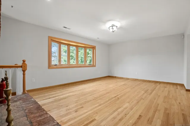 a view of an empty room with wooden floor fireplace and a window