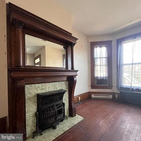a view of a livingroom with wooden floor and a fireplace