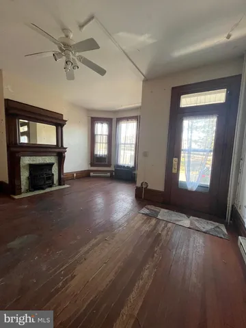an empty room with windows fireplace and wooden floor