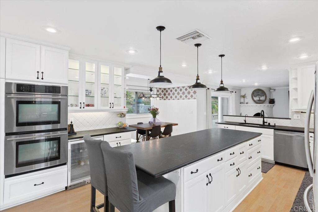32460 Lilac Road Valley Center, CA 92082 - Photo 8 of 45 a kitchen with stainless steel appliances granite countertop a sink a stove and chairs