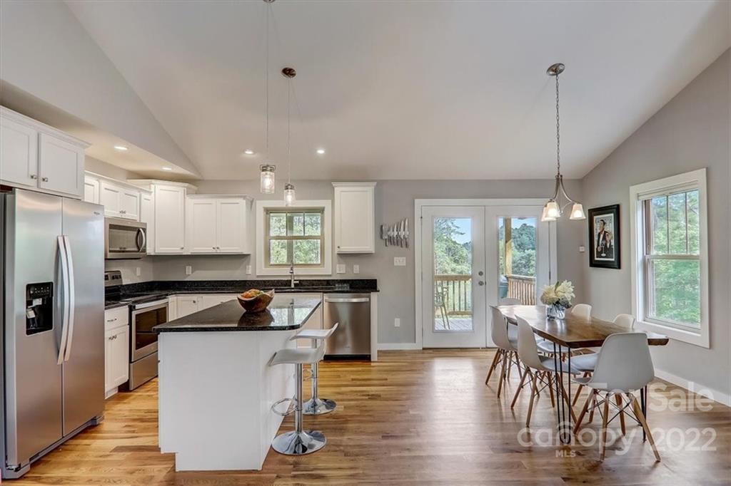 11 Ridge Brook Drive Weaverville, NC 28787 - Photo 12 of 38 a kitchen with a table chairs refrigerator and wooden floor