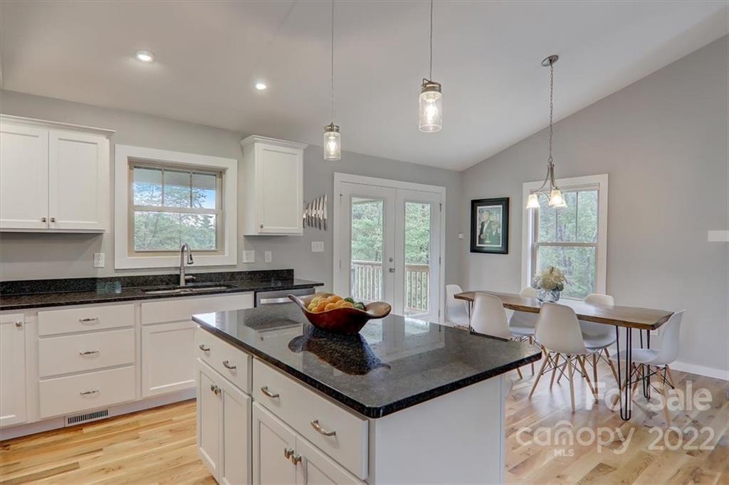 11 Ridge Brook Drive Weaverville, NC 28787 - Photo 15 of 38 a kitchen with white cabinets a sink dishwasher a dining table and chairs with wooden floor