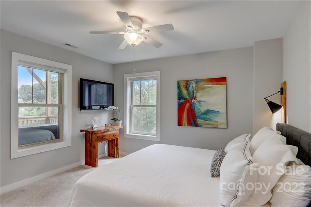 11 Ridge Brook Drive Weaverville, NC 28787 - Photo 24 of 38 a bedroom with a large bed a flat tv screen and a chandelier