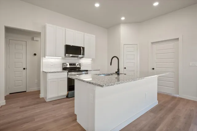 an empty room with wooden floor chandelier fan and windows