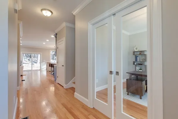 a view of hallway with wooden floor and a bathroom