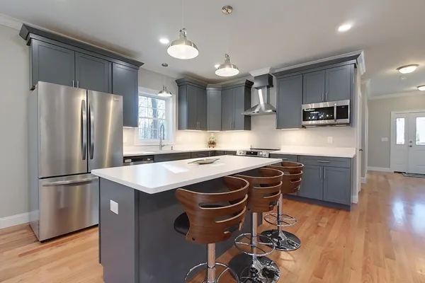 a kitchen with kitchen island a counter space a sink a refrigerator and a stove