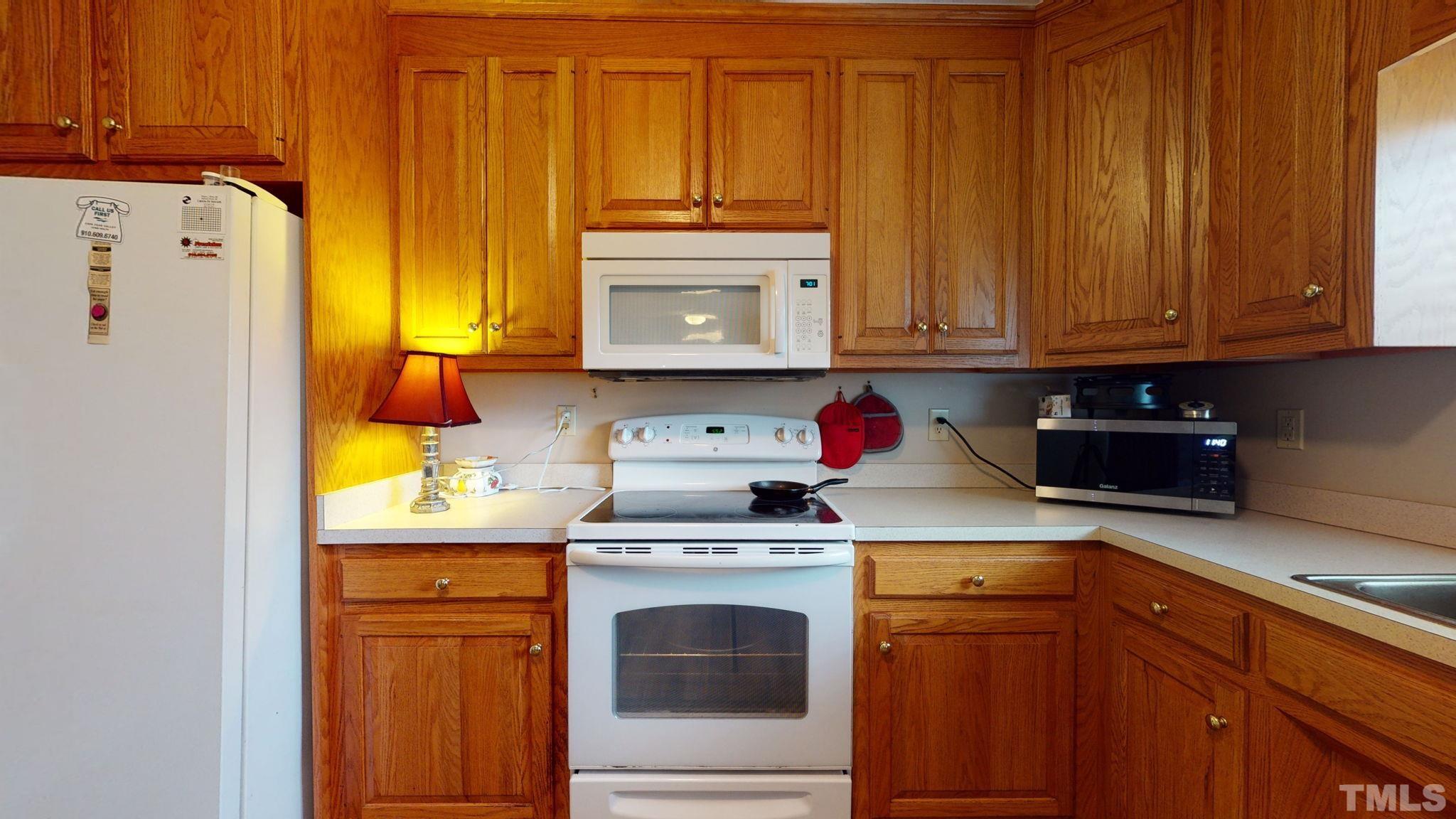 720 Mitchell Road Angier, NC 27501 - Photo 12 of 25 a kitchen with granite countertop wood cabinets and white appliances