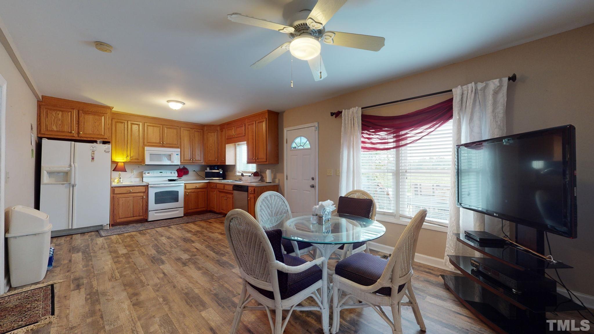 720 Mitchell Road Angier, NC 27501 - Photo 8 of 25 a kitchen with stainless steel appliances granite countertop a stove top oven a refrigerator a sink dishwasher a dining table and chairs with wooden floor