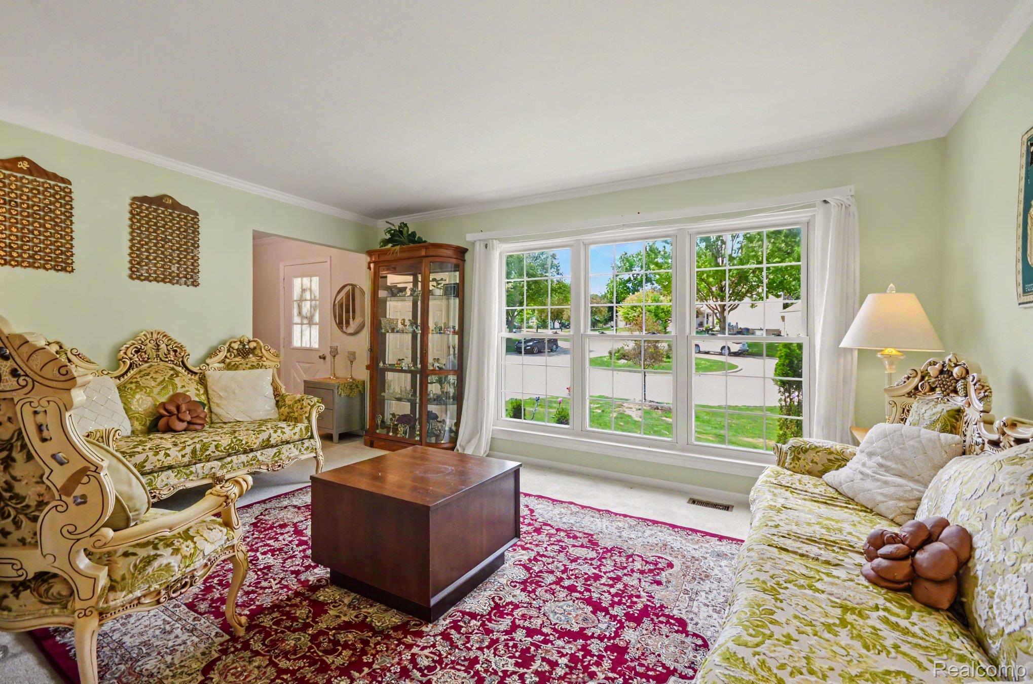 425 Thornridge Court Rochester, MI 48307 - Photo 15 of 35 Spacious living area featuring a large bay window with grid-patterned panes, crown molding, and light-colored wall finishes