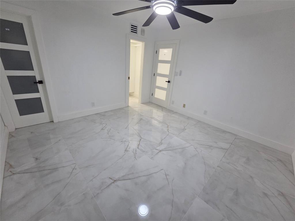 251 South Cypress Road, Unit 101 Pompano Beach, FL 33060 - Photo 17 of 41 en empty room with windows and ceiling fan