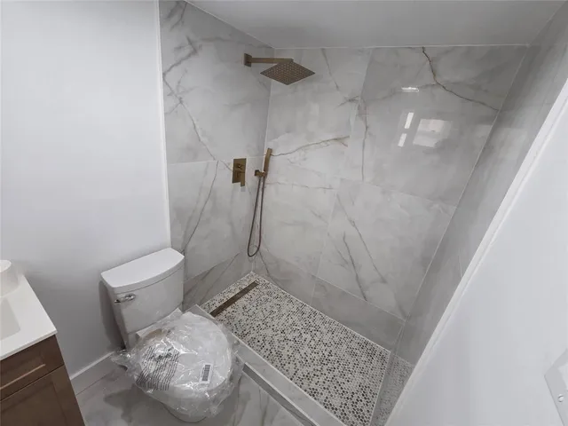 a white toilet sitting next to a white sink and vanity