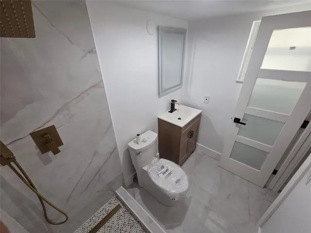 a bathroom with a granite countertop shower and a toilet