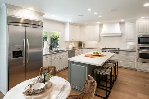 a kitchen with stainless steel appliances granite countertop a sink a microwave a refrigerator and wooden floor
