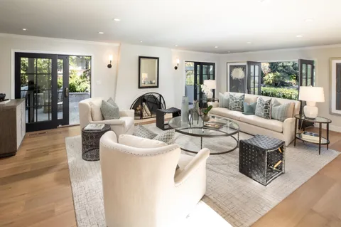 a living room with furniture large window and wooden floor