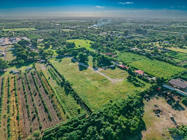 an aerial view of residential houses with outdoor space and trees