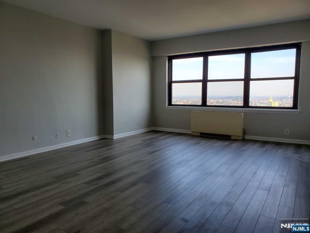 285 Aycrigg Avenue, Unit 22C Passaic, NJ 07055 - Photo 9 of 14 an empty room with wooden floor and windows