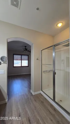 a view of empty room with wooden floor and fan