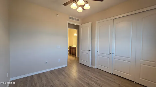 a view of an empty room with wooden floor and closet