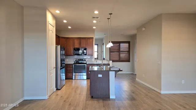 a kitchen with stainless steel appliances granite countertop a refrigerator a sink dishwasher a stove and a wooden floors