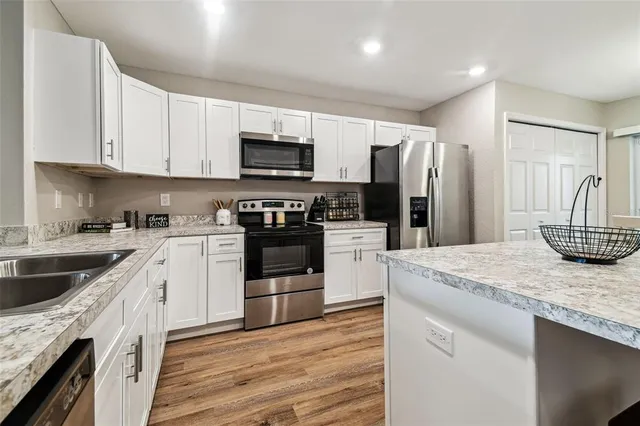 a kitchen with granite countertop white cabinets and stainless steel appliances