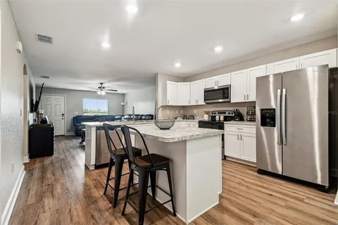 a kitchen with stainless steel appliances a microwave a sink a stove a refrigerator cabinets and dining table