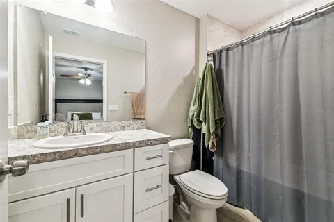 a bathroom with a granite countertop sink toilet and mirror