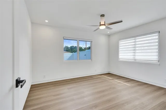 an empty room with windows and ceiling fan