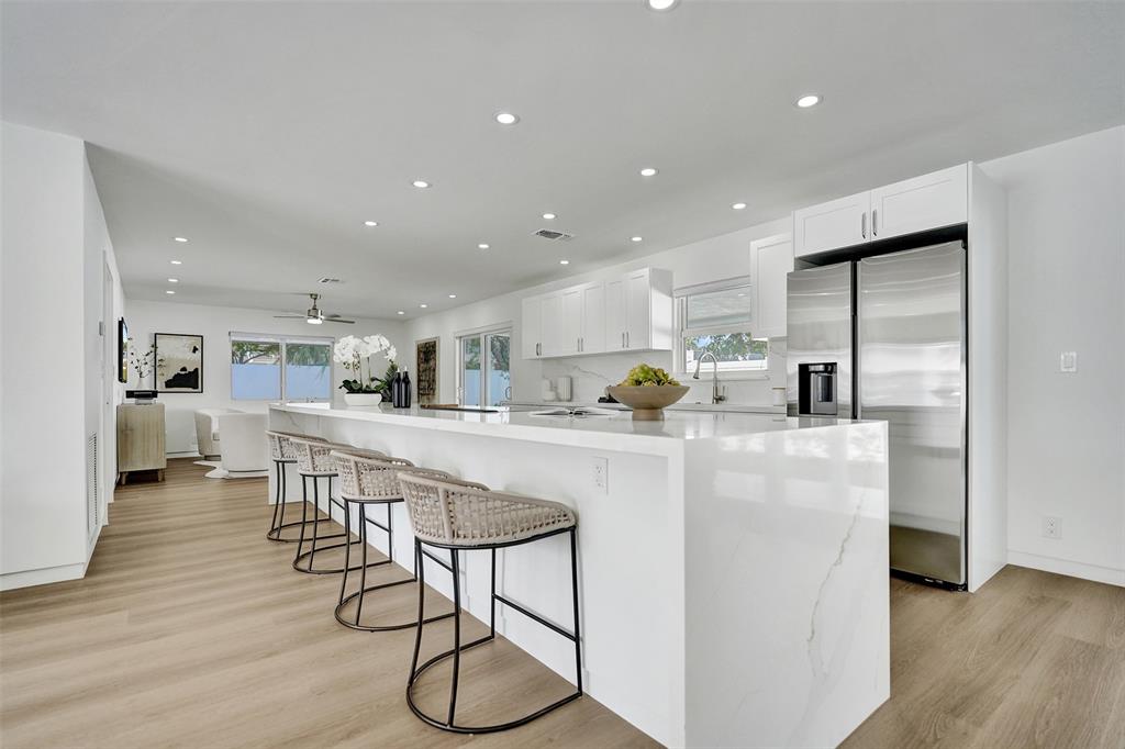 699 Northeast 70th Street Boca Raton, FL 33487 - Photo 10 of 66 a kitchen with stainless steel appliances kitchen island granite countertop a refrigerator a stove a microwave oven a dining table and chairs with wooden floor