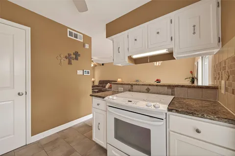 a kitchen with granite countertop a sink stove and cabinets