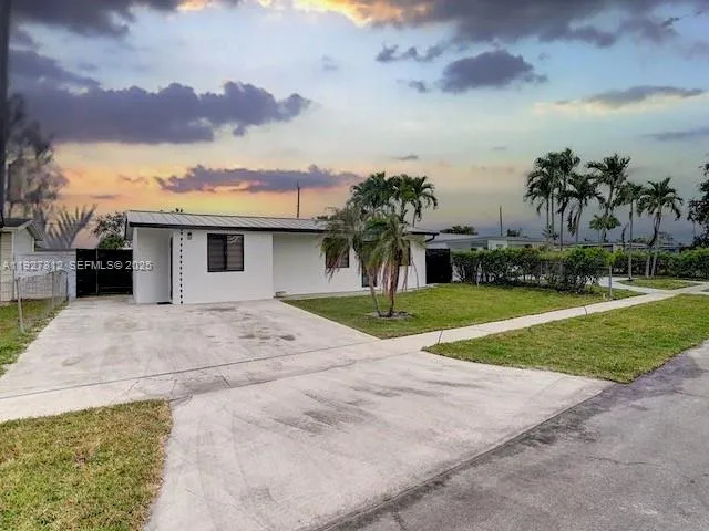 a view of a house with a yard and palm trees