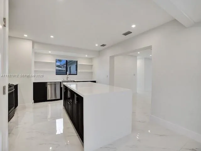 a large kitchen with a large counter top stainless steel appliances and cabinets