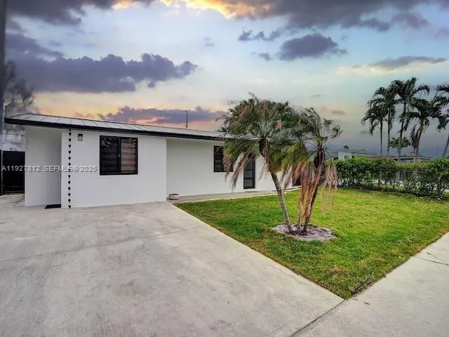 a front view of a house with a yard and palm trees