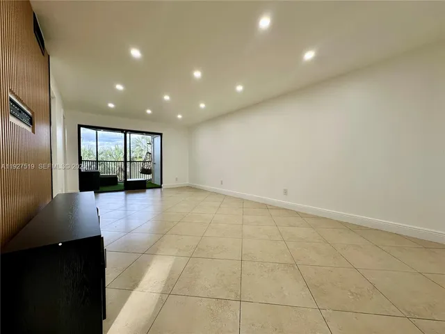 a view of an empty room with wooden floor and a bathroom