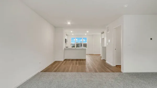 a room with wooden floor and a kitchen