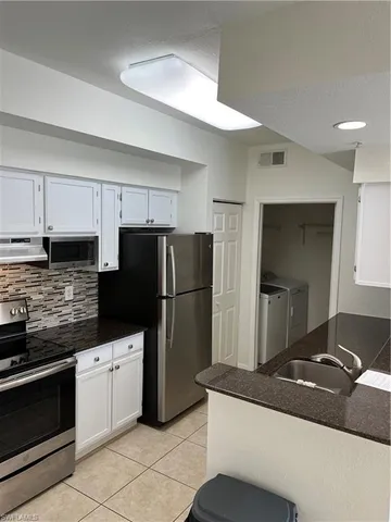 a kitchen with granite countertop a refrigerator and a stove top oven