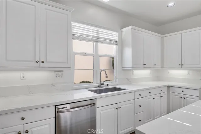 a kitchen with granite countertop white cabinets and a sink