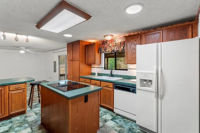a kitchen with stainless steel appliances granite countertop a refrigerator a sink a stove and a refrigerator