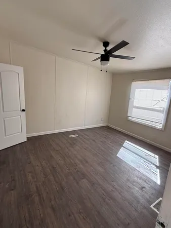 an empty room with wooden floor ceiling fan and windows